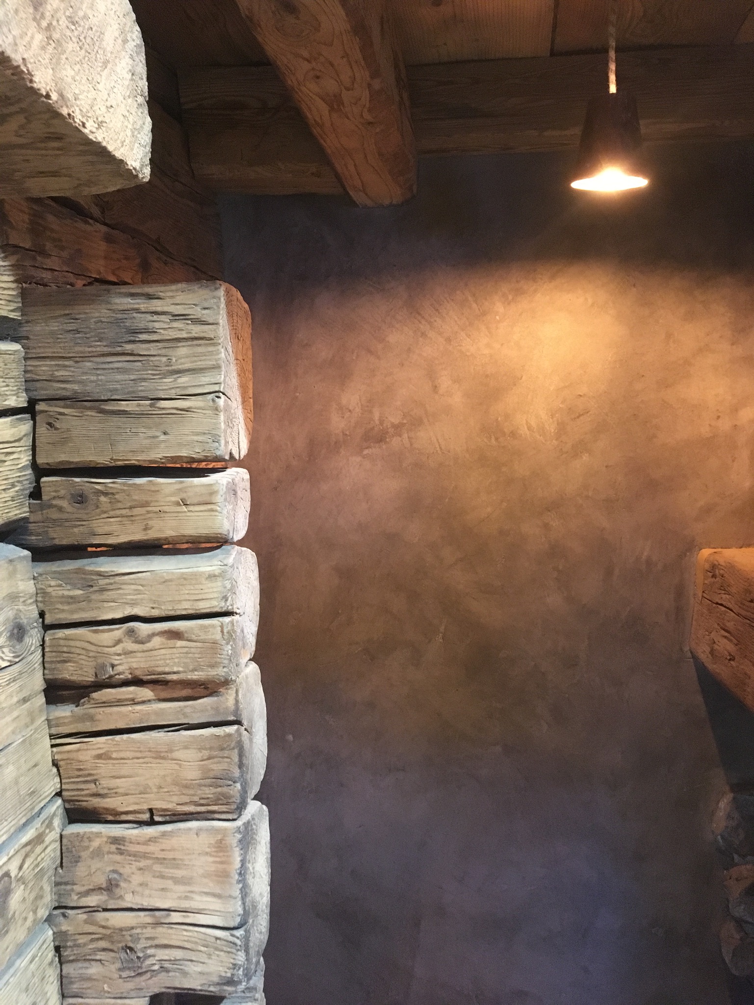 Mur d’accent enduit aux tons terre entre bois ancien
